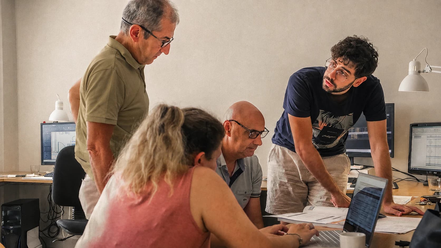 Equip professional col·laborant al voltant d'una taula de treball